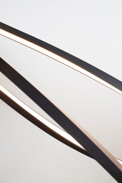 Detailaufnahme einer modernen schwarzen Pendelleuchte mit geschwungenen Lichtbändern