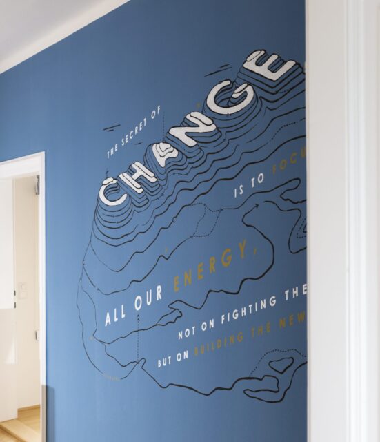 Blue office wall with a large-scale typographic illustration on the theme of change and focus