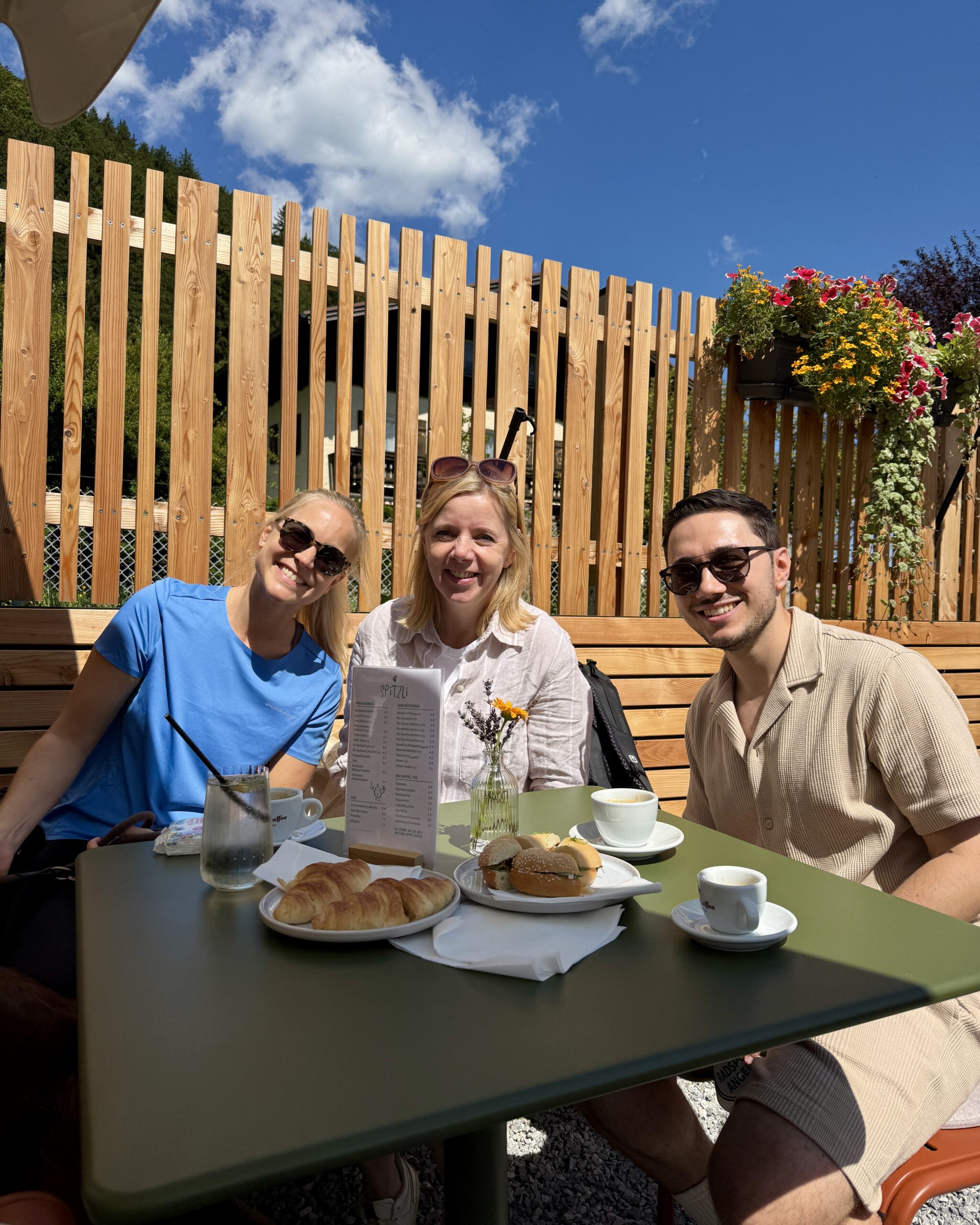 COX Teamtag im Bluntautal: Drei Mitarbeitende genießen gemeinsam eine Pause bei einem Kaffee.